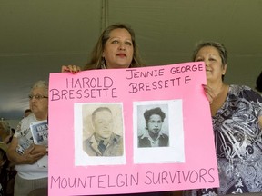 Heather Hammond, left, and her sister Janet George-Bressette hold photos of their parents who attended the former Mount Elgin Industrial Institute residential school at a ceremony on June 20, 2012, to unveil a monument to students who attended the school. The Chippewas of the Thames First Nation announced Thursday that a team will begin searching for unmarked graves on the grounds of the former school on its territory. (DEREK RUTTAN/ The London Free Press file photo)