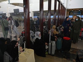 Passengers sit inside the departure terminal before boarding the Qatar Airways flight at the airport in Kabul on September 9, 2021.