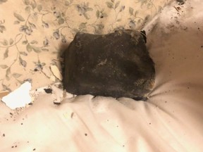 A meteorite rests on a bed inside a residential building in Golden, B.C., in an undated handout photo. Ruth Hamilton says she was sound asleep on Oct. 4 when she was awakened by her dog barking, the sound of a crash through her ceiling and the feeling of debris on her face. THE CANADIAN PRESS/HO-Ruth Hamilton