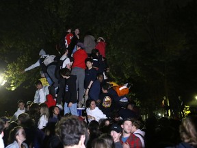 Students climb onto a playground structure in Victoria Park as they celebrate Queen's University homecoming in Kingston, Ont. on Sunday, Oct. 17, 2021.