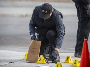 A member of the Special Investigations Unit places a glove in an evidence bag after a police officer shot and killed a man behind a plaza on Richmond Street near Pall Mall Street in London on Thursday, Oct. 28, 2021. (Derek Ruttan/The London Free Press)