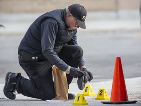 A member of the Special Investigations Unit places a tuque that appears to be stained with blood in an evidence bag on Oct. 28, 2021, after a London police officer shot and killed Justin Bourassa, 29, behind a plaza on Richmond Street near Pall Mall Street in London. (Derek Ruttan/The London Free Press)