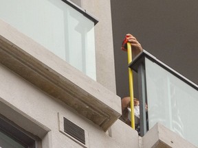 A man measures the gap in the railing on a 20th-floor balcony from which a toddler fell to her death last weekend. The little girl, named Inayah, was 22 months old. The highrise is at 400 Lyle St. in Old East Village in London. The grieving father identified the man pictured as an employee of Medallion Corp. that owns the building. Only one floor appears to show these gaps, on both the west and, this, the east side of the building. Some have barbecues placed strategically to cover the gap. Photograph taken on Thursday Oct. 7, 2021. Mike Hensen/The London Free Press