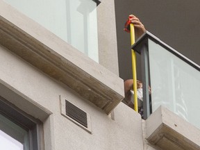 A man measures the gap in the railing on a 20th-floor balcony from which a toddler fell to her death last weekend. The little girl, named Inayah, was 22 months old. The highrise is at 400 Lyle St. in Old East Village in London. The grieving father identified the man pictured as an employee of Medallion Corp. that owns the building. Only one floor appears to show these gaps, on both the west and, this, the east side of the building. Some have barbecues placed strategically to cover the gap. Photograph taken on Thursday Oct. 7, 2021. Mike Hensen/The London Free Press