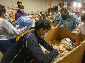 Food donations are up while cash giving was down compared to last year's London Food Bank Thanksgiving collection drive. From left, Natasha Solomon, Liam Solomon and Noah Solomon start to sort food at the food bank while Mystery Darko and Gonzalo Gomez-Vaza and Gael Gomez-Vaza pick up bags of unsorted donated food. "It's important to look out for our community," Natasha said of volunteering. (Mike Hensen/The London Free Press)