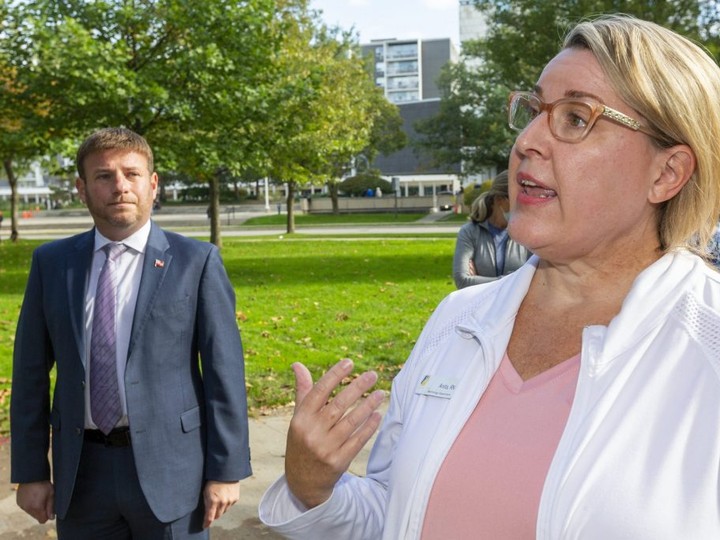  Anita Davis speaks to reporters after a rally in Victoria Park in London on Wednesday, Oct. 20, 2021 organized by United Health Care Workers of Ontario, a group that says it represents about 3,000 front-line workers in the province. Davis, who says she’ll soon be terminated for not being vaccinated, was wearing a name tag from the nephrology department at London Health Sciences Centre. Davis and Independent York Centre MPP Roman Baber, left, spoke at the rally that attracted about 40 people. (Mike Hensen/The London Free Press)