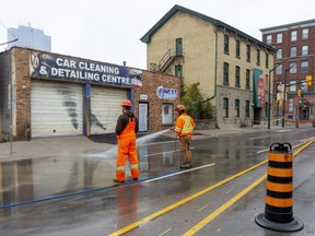 Workers from Enwave wash the mud off of York Street after a rough asphalt patch was installed in front of Finest Auto Detailing in downtown London.  An underground steam pipe ruptured Friday afternoon, blowing a large hole in the sidewalk and sending plumes of steam in the the air. No one was injured. Photograph taken on Sunday Oct. 31, 2021. (Mike Hensen/The London Free Press)