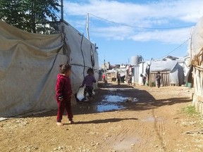 Syrian refugee children walk near tents at an informal tented settlement in Akkar, Lebanon October 19, 2021. Picture taken October 19, 2021. (REUTERS/Walid Saleh)