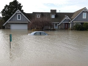 A home and car sit submerged in floodwaters on November 21, 2021 in Abbotsford, British Columbia. Residents and farmers continue to clean up and recover nearly a week after the Canadian province of British Columbia declared a state of emergency following record rainfall that resulted in widespread flooding of farms, landslides and the evacuation of residents. (Photo by Justin Sullivan/Getty Images)