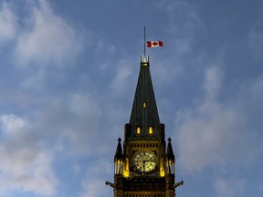 The Canadian flag flies at half mast atop the Peace Tower on Parliament Hill at sunset. Monday, Nov. 1, 2021.