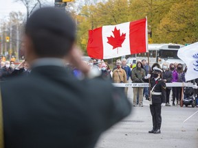 A member of the Royal Canadian Navy holds the Canadian flag during the Remembrance Day service at the cenotaph in London. Though only 100 people were invited to the event to keep number lows because of the COVID-19 pandemic, hundreds of turned out, including five busloads of veterans from Parkwood Institute.  (Derek Ruttan/The London Free Press)