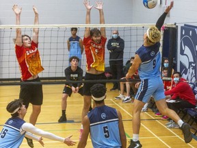 Lucas' Mitch von Dehn goes up for a spike against Jacob Johnson and Bryson Mitchell of Saunders during their senior boys volleyball match against Saunders at Lucas on Thursday November 4, 2021. Lucas won the first game 25-11. (Mike Hensen/The London Free Press)