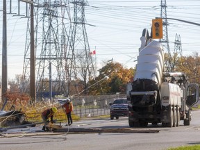 Workers clear debris at the intersection of Bradley Avenue and Pond Mills Road in London after a vacuum truck with its tank elevated drove through power lines and pulled some down. The power was out for large parts of White Oaks and other areas. No one was hurt. Photo taken Friday Nov. 5, 2021 (Mike Hensen/The London Free Press)