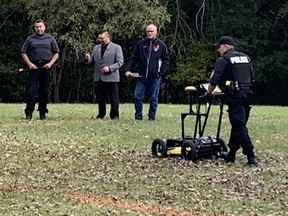 A police officer uses a ground-penetrating radar unit Tuesday as the search begins for unmarked graves on the grounds of the former Mohawk Institute residential school in Brantford. (Vincent Ball/Postmedia Network)