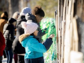 A group gathers in solidarity with Fatemeh Anvari, a teacher removed from her classroom at an elementary school in Chelsea, Que., for wearing a hijab under Quebec's Bill 21 secularism law, by tying green ribbons to the fence of the school. Three London city councillors will introduce a motion Tuesday asking city council to contribute $100,000 to a legal challenge of the Quebec legislation. (Postmedia Network files)