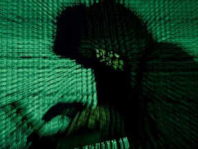 A man holds a laptop computer as cyber code is projected on him in this illustration picture taken on May 13, 2017.