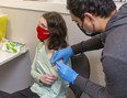 Madeline Goldhawk, 23, who is immuno-compromised, gets a COVID-19 vaccine booster dose from pharmacist Chintan Patel at London’s Knight Hill Pharmacy on Thursday, Dec. 16, 2021. (Mike Hensen/The London Free Press)