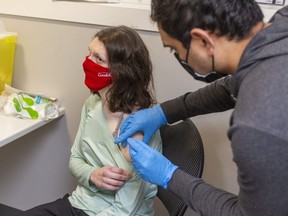 Madeline Goldhawk, 23, who is immuno-compromised, gets a COVID-19 vaccine booster dose from pharmacist Chintan Patel at London’s Knight Hill Pharmacy on Thursday, Dec. 16, 2021. Alex Summers, acting medical officer of health for Middlesex-London, is urging people seeking booster shots to be patient as officials ramp up to meet the increased demand from people seeking protection from the Omicron variant driving COVID-19 infections in the London area. (Mike Hensen/The London Free Press)