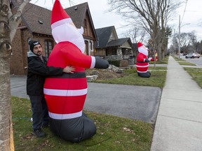 Lucas De Nard, who lives on Thornton Avenue in London, picks up his fallen inflatable Santa on the North London street full of them. "I didn't buy this Santa," De Nard said of the inflatable that just showed up at his house one day. He then went out and bought one for another resident of the street. "One week there was about three, next week there were 10," he said. "It definitely gives you a feeling of community." (Mike Hensen/The London Free Press)