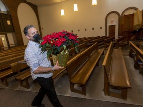 Rod Tramble brings poinsettias into St. John the Divine Church on Baseline Road in London. Like all Roman Catholic churches in the city, St. John will be holding in-person worship services over Christmas, although other churches in London have opted out amid a COVID-19 surge. (Mike Hensen/The London Free Press)