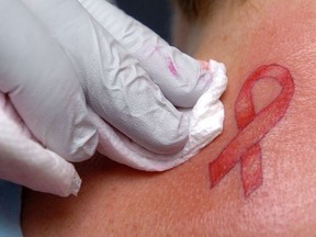 A customer gets a pink-ribbon tattoo. The symbol is ubiquitous and unregulated, and some companies exploit that fact.