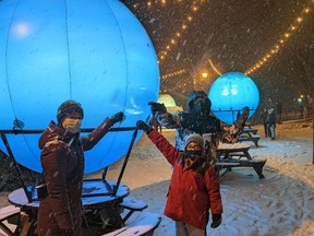 Lights On Stratford general manager Kaileigh Krysztofiak, seven-year-old Jaxon Brooks and Destination Stratford executive director Zac Gribble point out the storm in Neptune's southern hemisphere that recently led Jaxon to realize Neptune and Uranus were out of order in the winter lights festival's Journey to the Stars exhibit on Tom Patterson Island. (Galen Simmons/the Beacon Herald)