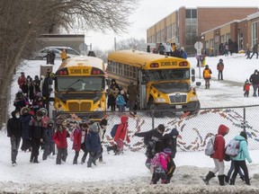 Students at Eagle Heights elementary school on Oxford Street in London walk to their buses at the end of a school day this week. Students began in-person learning Monday after attending classes online the previous two weeks. (Mike Hensen/The London Free Press)