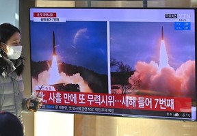 A woman walks past a television screen showing a news broadcast with file footage of a North Korean missile test, at a railway station in Seoul on January 30, 2022, after North Korea fired a "suspected ballistic missile" in the country's seventh weapons test this month according to the South's military. (Photo by Jung Yeon-je / AFP)