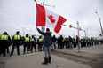 A protester waves a Canadian flag as police officers stand guard on a street in Windsor, Ontario. File photo