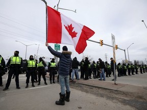 A protester waves a Canadian flag as police officers stand guard on a street in Windsor, Ontario. File photo