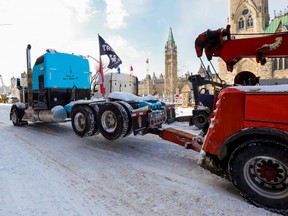 A truck is towed from in front of Parliament Hill as police work to restore normality to the capital after trucks and demonstrators occupied the downtown core for more than three weeks to protest against pandemic restrictions.