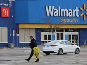 A London police officer removes police tape used to cordon off a section of the parking lot at Argyle Mall, where a bomb threat forced the evacuation of multiple stores including Walmart and Winners on Sunday. DALE CARRUTHERS / THE LONDON FREE PRESS