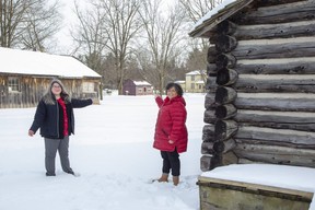 Dawn Miskelly, left, executive director of Fanshawe Pioneer Village, and Christina Lord, member of London's Black History Coordinating Committee, point to the proposed location of the Fugitive Slave Chapel between the village's log school and the blacksmith shop.  A campaign was launched in February to raise $300,000 to move the chapel from its current location on Gray Street to the Pioneer Village.  (Derek Ruttan/The London Free Press)