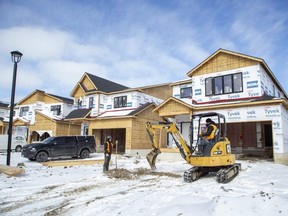 Lucas Byrne and heavy machine operator Jason Lima of ASG Excavating work on a new subdivision by Foxwood Homes in the northwest corner of London. (Derek Ruttan/The London Free Press)
