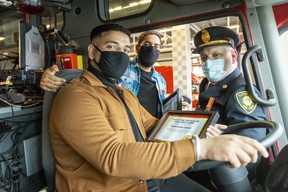 Yuvi Saini, left, Avi Verma and deputy fire chief Richard Hayes pose in a London fire truck after Saini and Verma received awards for their heroic nighttime rescue of three women from a burning home at 1281 Hillcrest Ave.  on Feb.  1. Hayes said the two men saved the lives of the three women who were trapped in the basement as smoke and flames filled the home.  Photograph taken Friday, Feb.  11, 2022. (Mike Hensen/The London Free Press)