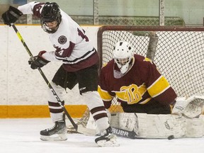 South's Charlie Smith goes between the legs to centre the puck in front of Banting goalie Henry Menary during the second period of their game at Nichols arena in London, Ont. (Mike Hensen/The London Free Press)
