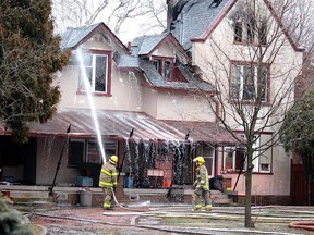 Firefighters work to put out hotspots Thursday morning at this Elgin Street home in Wallaceburg that caught fire around 2 a.m., resulting in the death of three people. PHOTO Ellwood Shreve/Postmedia News