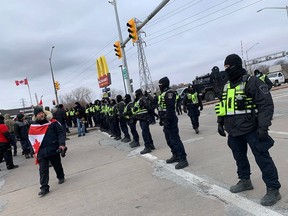 Police officers from Windsor, London, and other jurisdictions line up across Huron Church Road on Saturday, Feb. 12, 2022, encouraging protesters to leave after blocking access to the Ambassador Bridge for days. PHOTO BY DAX MELMER /Windsor Star
