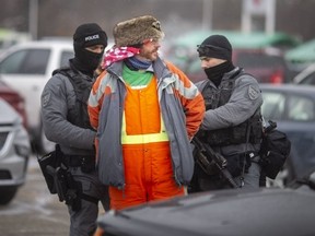 A man is arrested as police push back protesters congregating around the Ambassador Plaza at Huron Line and Tecumseh Road in Windsor on Sunday, Feb. 13, 2022. (Dax Melmer/Postmedia Network)