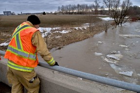 A Sebringville firefighter keeps an eye on a section of Whirl Creek from a bridge on Road 160, near Frank Street, in Mitchell on Sunday March 6, 2022. A girl, 10, had fallen through the ice hours earlier.  Chris Montanini/Stratford Beacon Herald