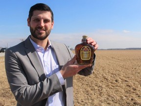Matthew Slotwinski, senior development officer with the Sarnia-Lambton Economic Partnership, holds a bottle of Crown Royal whisky at the planned site of a new distillery. Diageo announced plans Wednesday to build a $245-million plant on Moore Line in St. Clair Township south of Sarnia. (Paul Morden/Postmedia Network)
