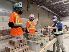 Hopeton Powell, left, and Tyson Proper learn how to properly lay brick from instructor Ian Maitin at the Ontario Masonry Training Centre in London. The centre was the location used by Ministry of Labour Monte McNaughton to announce $28 million earmarked for free pre-apprenticeship programs. JONATHAN JUHA/The London Free Press