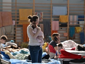 A woman holds her two-month-old baby in a temporary shelter in a gym of a high school in Przemysl, near the Ukrainian-Polish border, on March 15, 2022.  More than three million people have now fled Ukraine since Russia invaded on Feb. 24, the United Nations said on March 15, 2022. (Photo by LOUISA GOULIAMAKI/AFP via Getty Images)