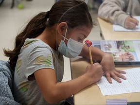 A pupil is shown doing school work in class. (Photo by PAUL RATJE/AFP via Getty Images)