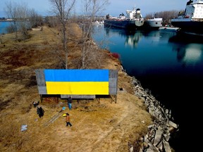 Painter Fred Mast, Terry Glover, left, and Josh Saunders turn a blank billboard near the city's harbour into a show of support for embattled Ukraine.  (Tim Kozachuk photo)
