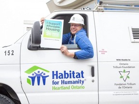 Habitat For Humanity building manager George De Vlugt holds an oversized version of stickers the non-profit group is distributing in London. (Derek Ruttan/The London Free Press)