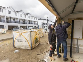 Kaleb Ellul-Barnes and Dave Romkes of Stewart Overhead Doors adjust a garage door in a new townhouse development nearing completion at Hyde Park and Sunningdale roads in London. Photograph taken on Thursday, April 21, 2022. (Mike Hensen/The London Free Press)