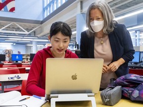 Jeri Fan, 17, a Grade 12 student at Oakridge secondary school in London, is doing a digital co-op placement with high tech giant Apple.  Co-op teacher Martha McIntosh helps Fan with her work on Wednesday, April 27, 2022. (Mike Hensen/The London Free Press)