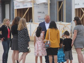 Premier Doug Ford speaks with some families at a new housing development in London's Glen Cairn neighbourhood during a campaign stop in the city on Saturday May 21, 2022. At left is Jane Kovarikova, the Progressive Conservative candidate in NDP-held London-Fanshawe. (JONATHAN JUHA/The London Free Press)