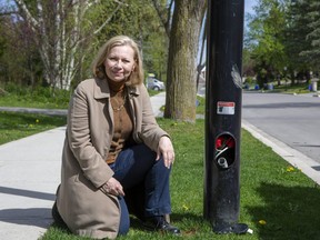 Cristine de Clercy kneels beside a street light in her north London neighbourhood that was stripped of copper wire by thieves on Easter weekend. The theft of copper wire from streetlights cost the city $335,000 to repair in 2021, a city official said. (Derek Ruttan/The London Free Press)